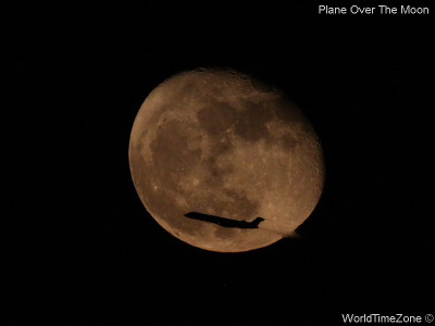 A plane flies in front of the Moon by worldtimezone
