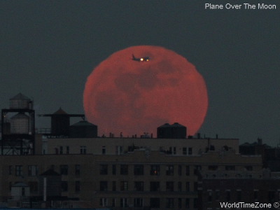 A plane flies in front of the Moon by worldtimezone