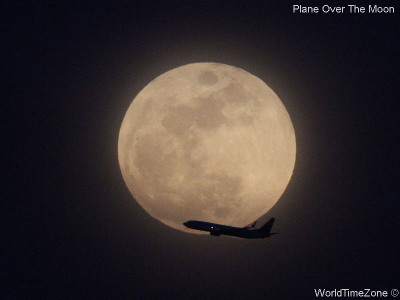 A plane flies in front of the Moon by worldtimezone